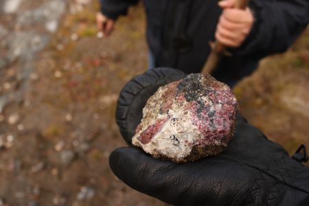 A resident holds a rock sample unearthed by exploration for Heavy Rare Earth Elements. Photo by Claire Stewart-Kanigan